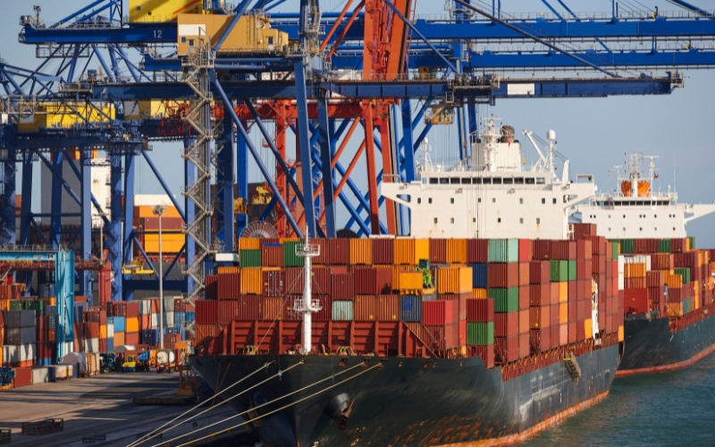 A large container ship docked at a port, symbolizing global trade and shipping efficiency.