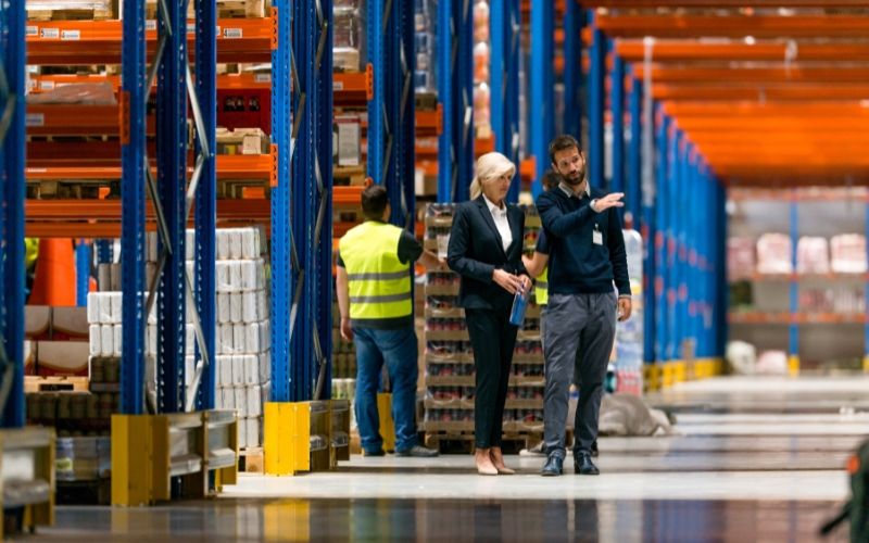 Two people in a warehouse aisle, engaged in a conversation about who qualifies for IC-DISC rules.