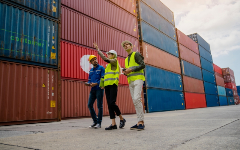 A group of people wearing safety vests are next to shipping containers, providing an update on IC-DISC dividends.