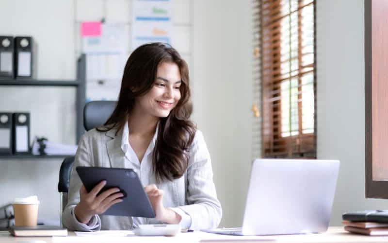 A woman dressed in a business suit engages with a tablet, examining FAQs about reviewing IC-DISC structures.