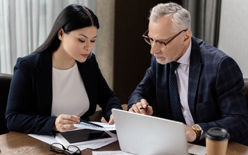 Two professionals in business attire work together on a laptop, focusing on IC-DISC tax strategies for U.S. exporters.