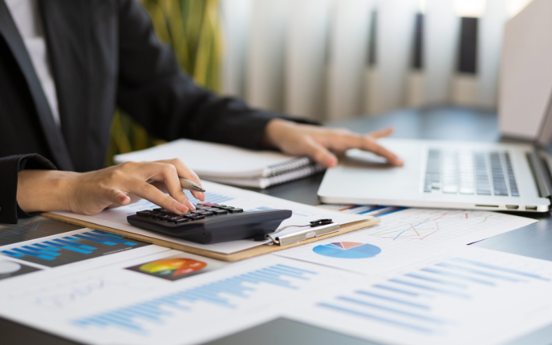 A businesswoman at her desk, using a calculator and laptop to analyze IC-DISC strategies for U.S. exporters.