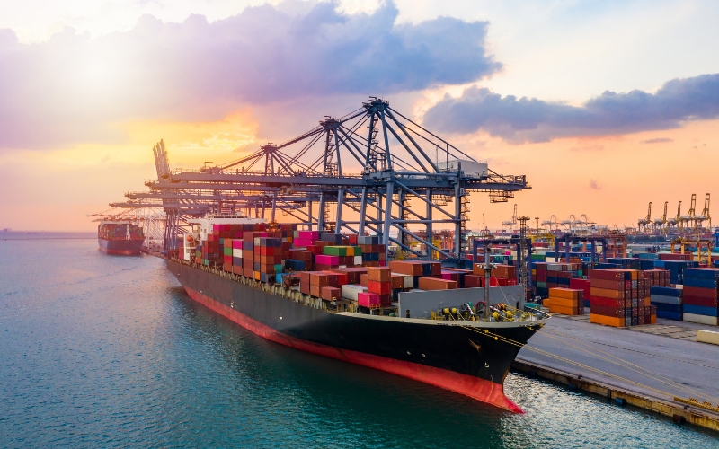 A large container ship navigates the water during sunset, representing the benefits of IC-DISC for U.S. exporters.