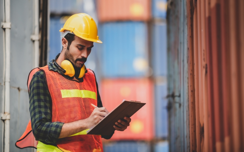 A man in a hard hat and safety vest is holding a clipboard, preparing to discuss the 1120-IC-DISC Schedule K instructions.