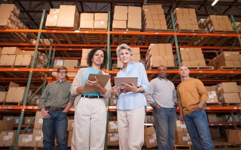 Several individuals gather in a warehouse filled with boxes, focusing on common IC-DISC errors and the need for expert assistance.