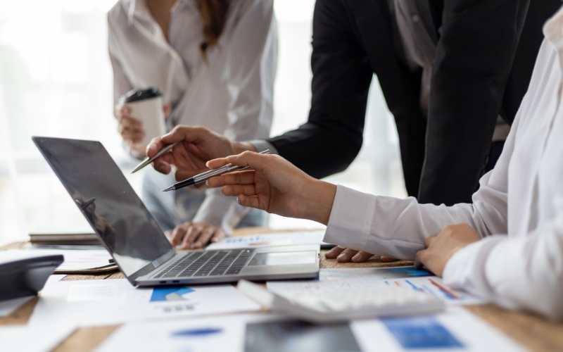 Business professionals collaborating on a laptop in an office, focusing on common IC-DISC errors in recordkeeping.