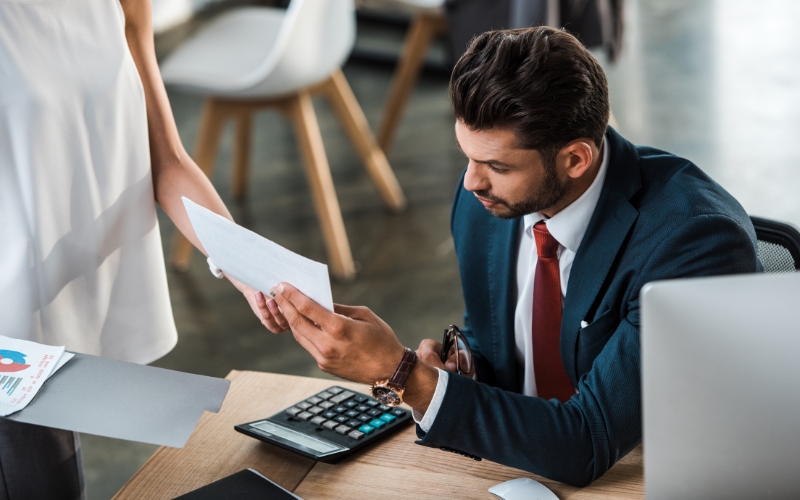 A man and woman at a desk with a calculator and documents, focused on calculating export tax incentives and savings.