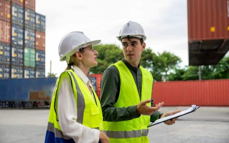 Two professionals in hard hats engaged in a conversation about the importance of documentation for export tax incentives.