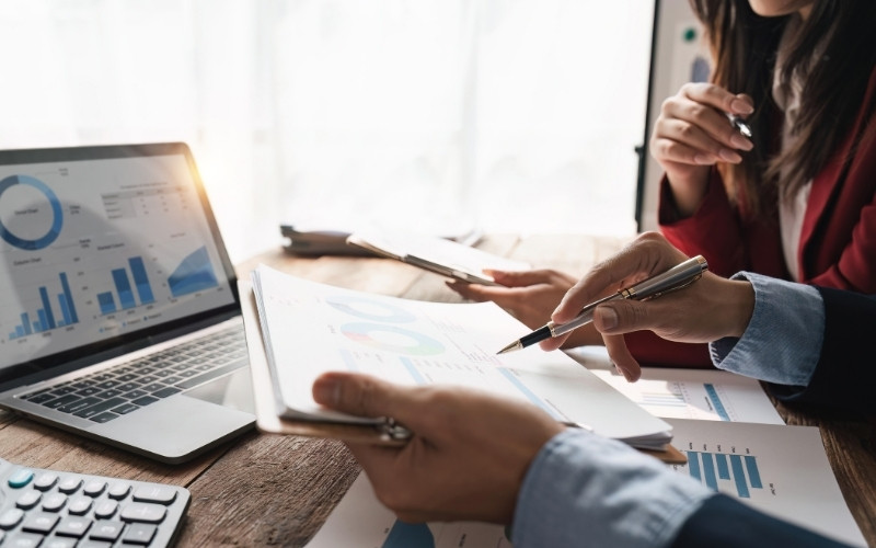 Group of business individuals working on a laptop, examining graphs and papers about IC-DISC vs. FDII for 2026 analysis.